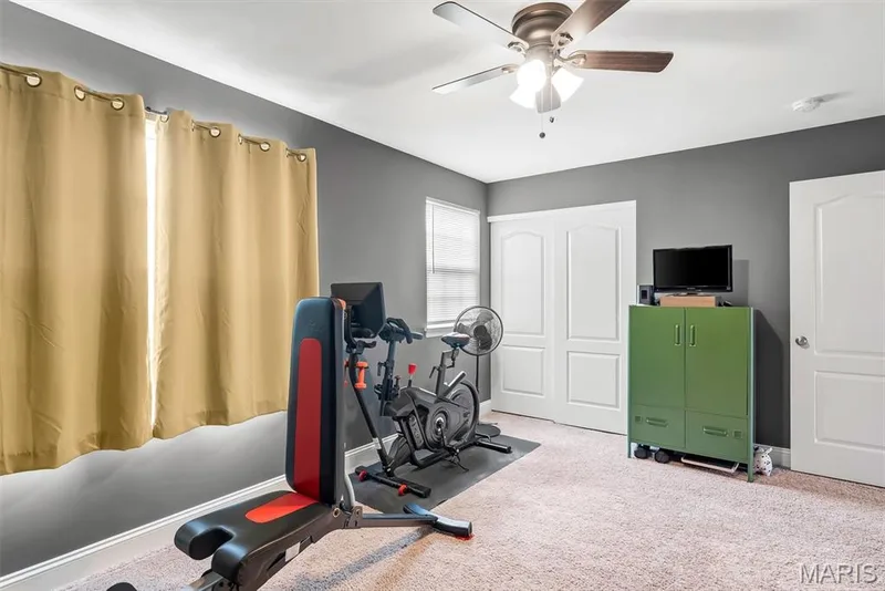Versatile bonus room featuring carpeted flooring, ceiling fan with integrated lighting, gray painted walls, and ample closet storage — 225 Thorn Brook Drive, O'Fallon, MO 63366