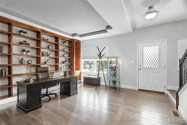 Expansive built-in shelving, wood-finish flooring, a decorative front entry door with a privacy pane, and a tray ceiling with recessed lighting — 225 Thorn Brook Drive, O'Fallon, MO 63366