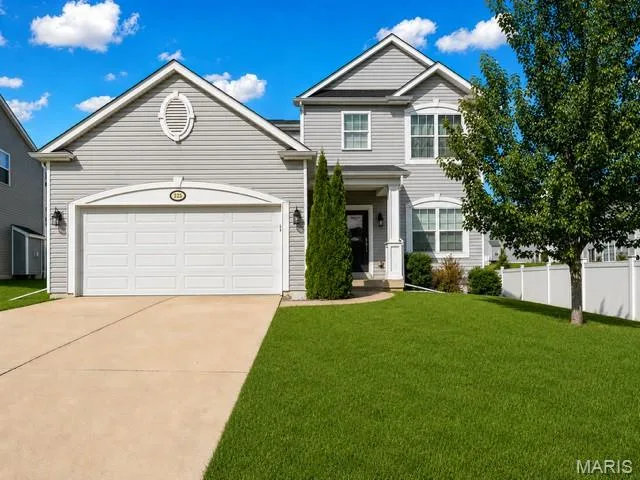 Two-story residence featuring light gray siding, white trim, an attached two-car garage, a concrete driveway, and a front lawn — 225 Thorn Brook Drive, O'Fallon, MO 63366