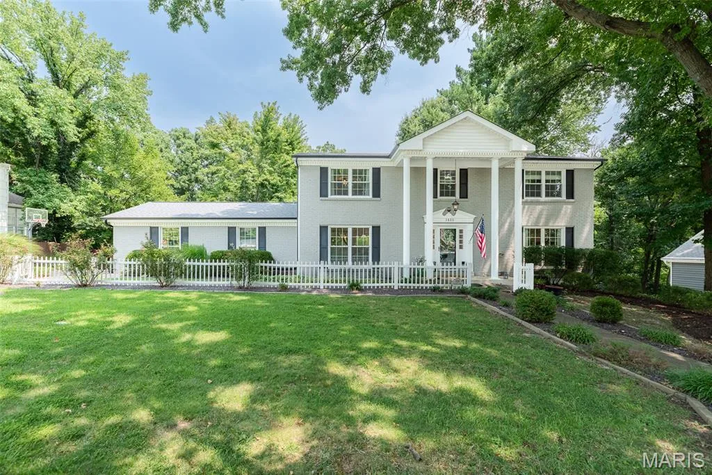Colonial-style exterior featuring a portico with four columns, a white picket fence, and dark-framed windows with shutters — 1526 Candish Lane, Chesterfield, MO 63017