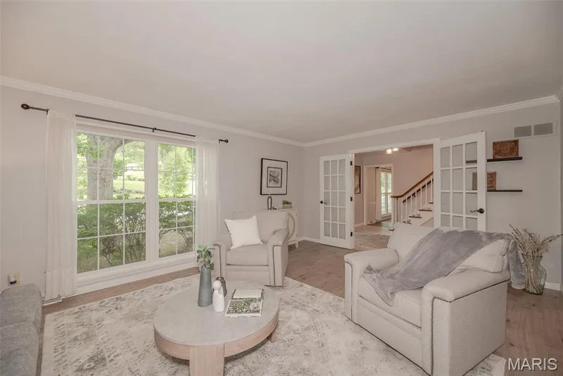 Bright living area featuring large windows, wood-finish flooring, and French doors — 1526 Candish Lane, Chesterfield, MO 63017