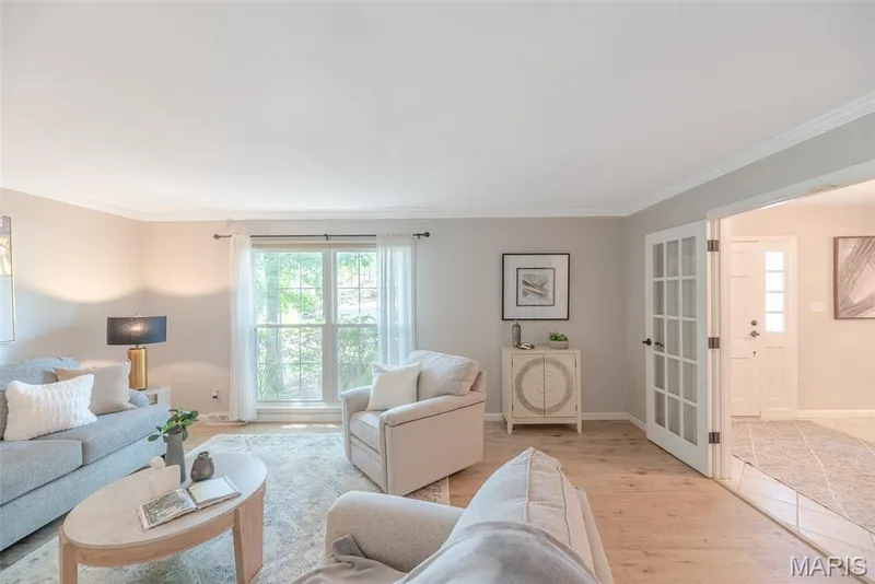 Bright primary bedroom suite featuring hardwood flooring, large multi-pane windows with natural light, walk-in closet with glass-paneled doors, ensuite bathroom with tile flooring, and a spa-like soaking tub adjacent to the sleeping area — 1526 Candish Lane, Chesterfield, MO 63017