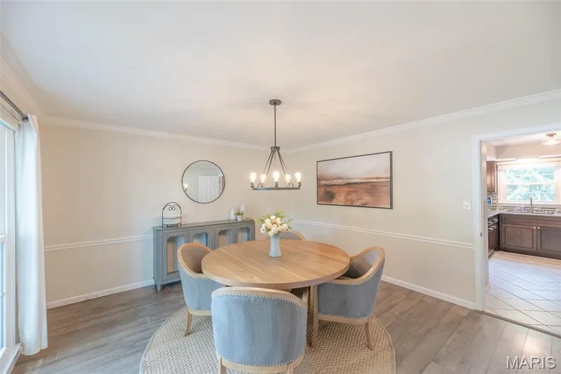 Elegant dining space featuring a round wood-finish table, blue upholstered chairs, and wide-plank wood flooring — 1526 Candish Lane, Chesterfield, MO 63017