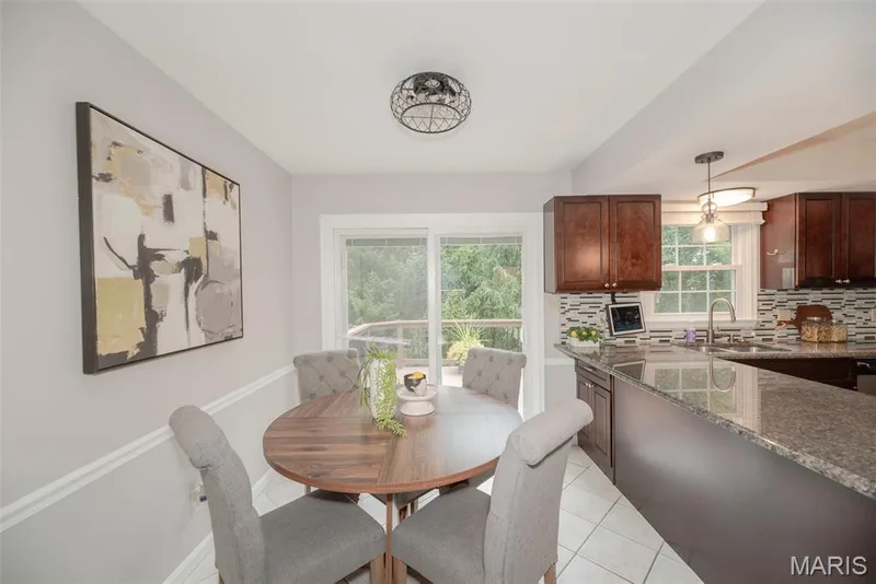 Kitchen featuring dark wood-finish cabinetry, a stone countertop, a tile backsplash, and a stainless steel sink with a gooseneck faucet — 1526 Candish Lane, Chesterfield, MO 63017