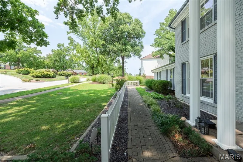 Brick exterior with white columns, brick paver walkway, manicured lawn, and mature trees — 1526 Candish Lane, Chesterfield, MO 63017
