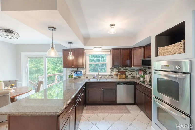 Chef's kitchen featuring rich wood cabinetry, stainless steel double wall ovens, gas cooktop with tile backsplash, and quartz countertops — 1526 Candish Lane, Chesterfield, MO 63017