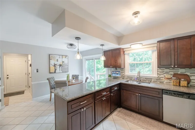 Kitchen featuring dark wood cabinetry, granite countertops, a tile backsplash, and stainless steel appliances — 1526 Candish Lane, Chesterfield, MO 63017
