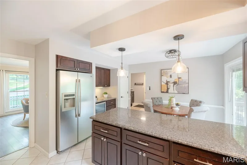 Kitchen featuring dark wood-finish cabinetry, stainless steel refrigerator, and granite countertops — 1526 Candish Lane, Chesterfield, MO 63017
