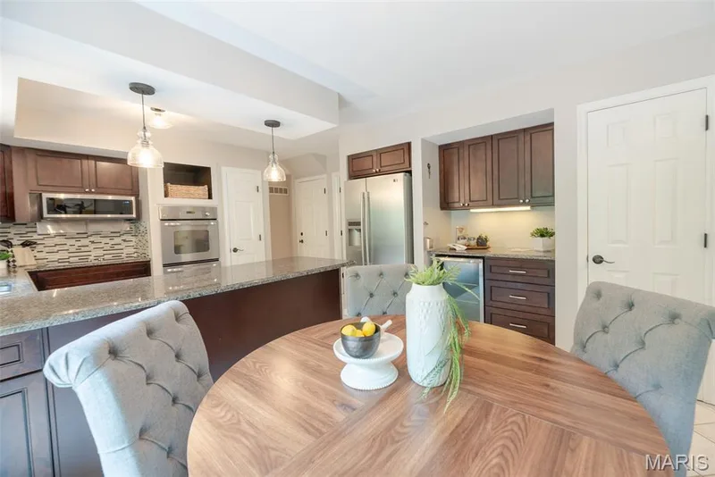 Kitchen featuring dark wood cabinetry, stainless steel appliances, granite countertops, tile backsplash, and recessed lighting — 1526 Candish Lane, Chesterfield, MO 63017