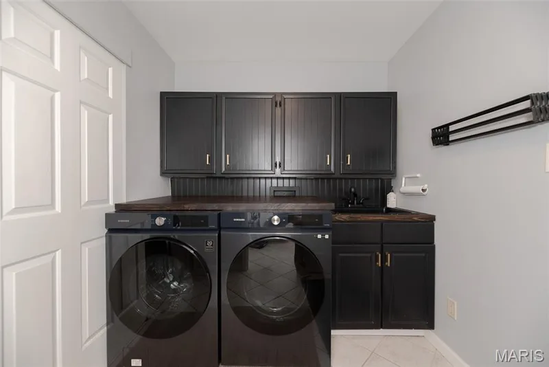 Laundry area featuring dark cabinetry, dark countertop, and an integrated sink — 1526 Candish Lane, Chesterfield, MO 63017