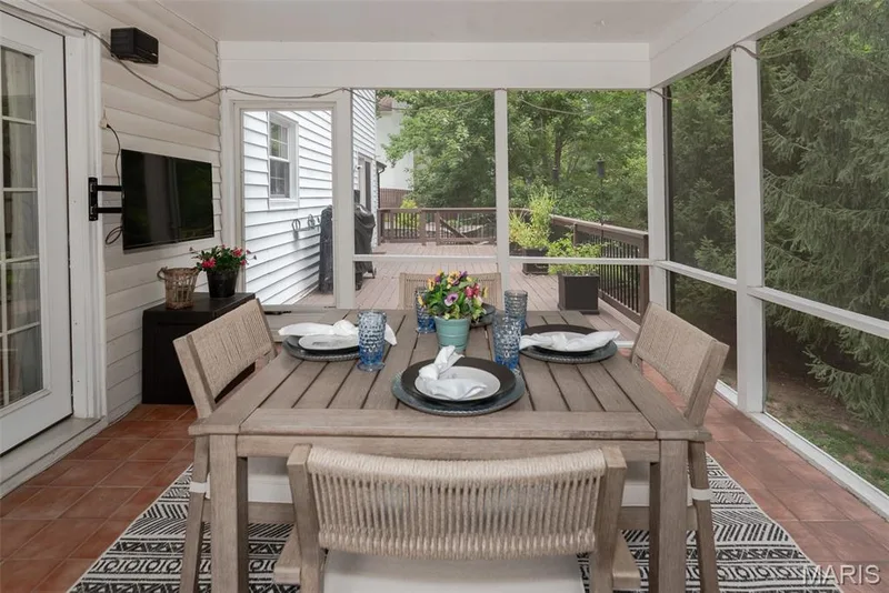 Screened porch featuring terracotta-style tile flooring, white siding, and direct access to an exterior wood deck — 1526 Candish Lane, Chesterfield, MO 63017
