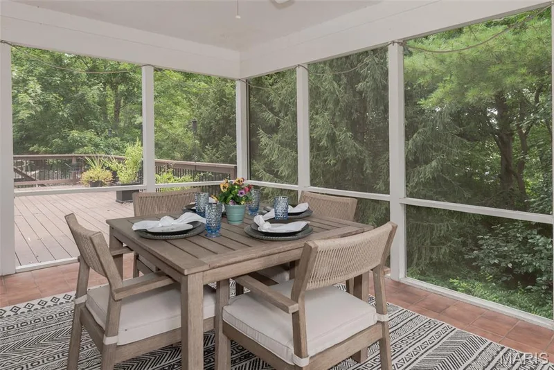 Screened outdoor living space featuring a terracotta-hued tile floor and a wooden deck — 1526 Candish Lane, Chesterfield, MO 63017