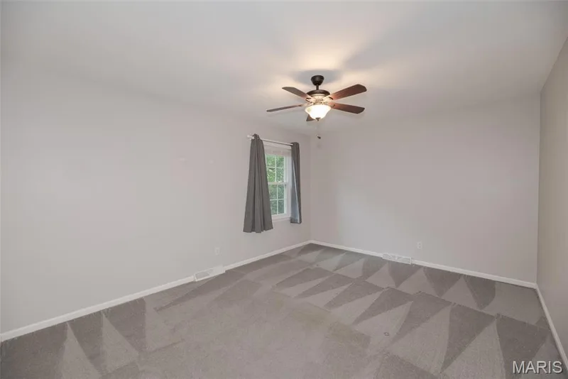 Neutral wall color, window with natural light, ceiling fan with integrated lighting, and patterned carpeting — 1526 Candish Lane, Chesterfield, MO 63017