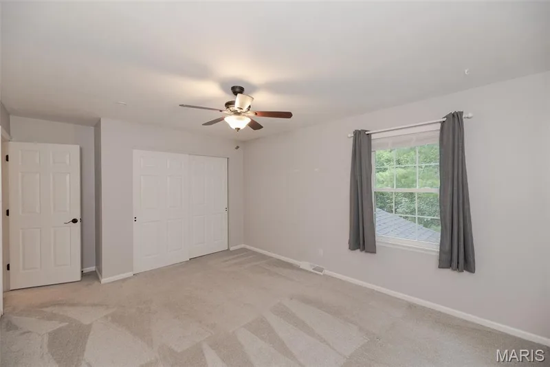 Neutral wall color, wall-to-wall carpeting, ceiling fan with integrated lighting, paneled doors, and a window with exterior scenery — 1526 Candish Lane, Chesterfield, MO 63017