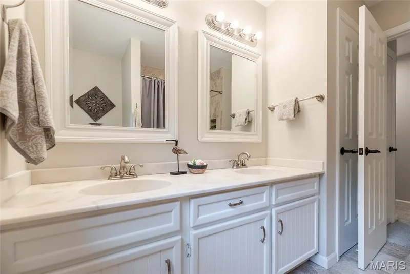 Dual-vanity bathroom featuring white cabinetry with soft-close drawers, polished chrome faucets, and a continuous countertop with integrated sinks — 1526 Candish Lane, Chesterfield, MO 63017