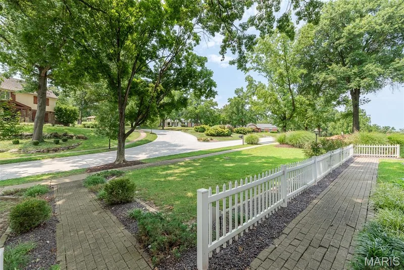 Paved pathways bordered by a white picket fence, expansive green lawn, and mature trees — 1526 Candish Lane, Chesterfield, MO 63017
