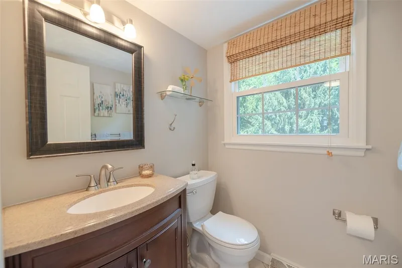 Vanity with an integrated sink, a framed mirror, and a window with a bamboo shade — 1526 Candish Lane, Chesterfield, MO 63017