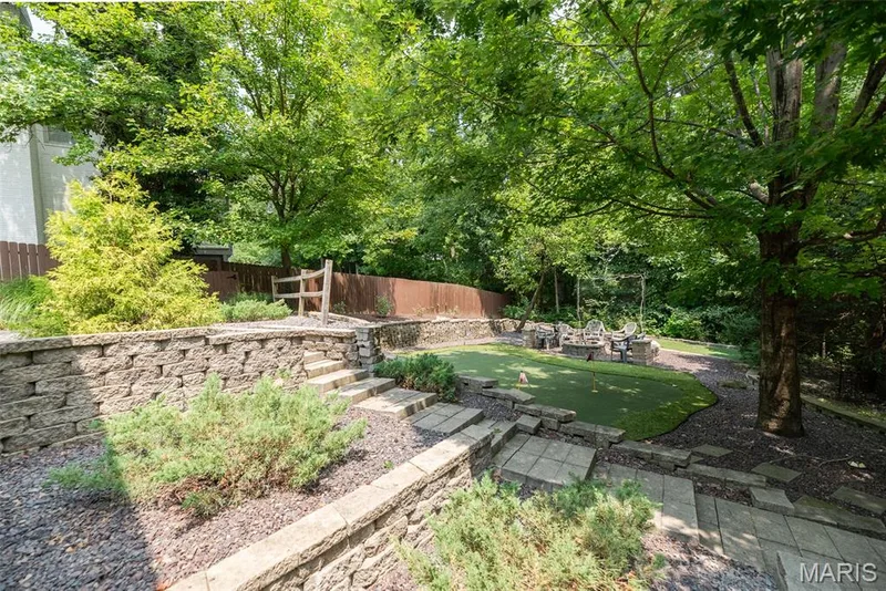 Tiered retaining walls with integrated landscaping, stone step pathways, mature trees, and a putting green — 1526 Candish Lane, Chesterfield, MO 63017