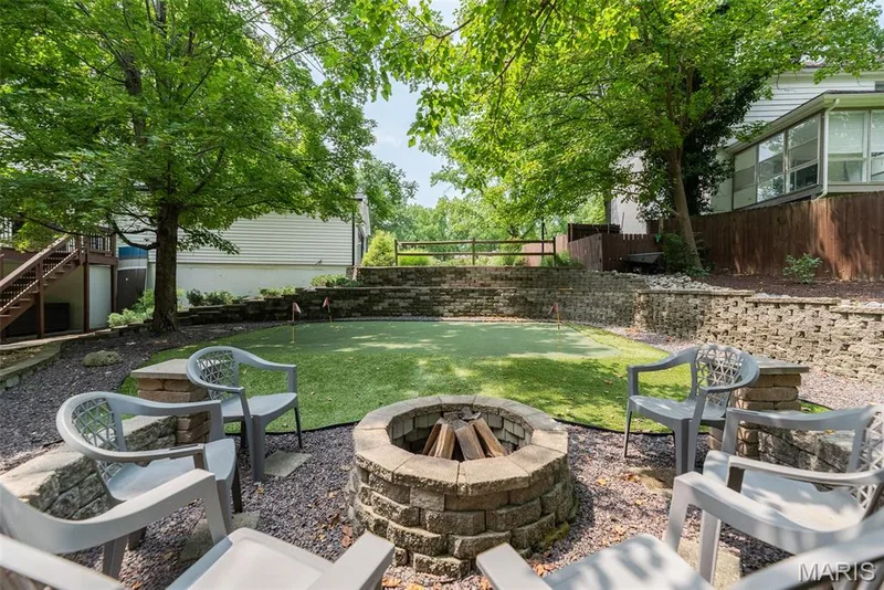 Expansive terraced yard featuring a putting green, a stone-built fire pit, and retaining walls — 1526 Candish Lane, Chesterfield, MO 63017