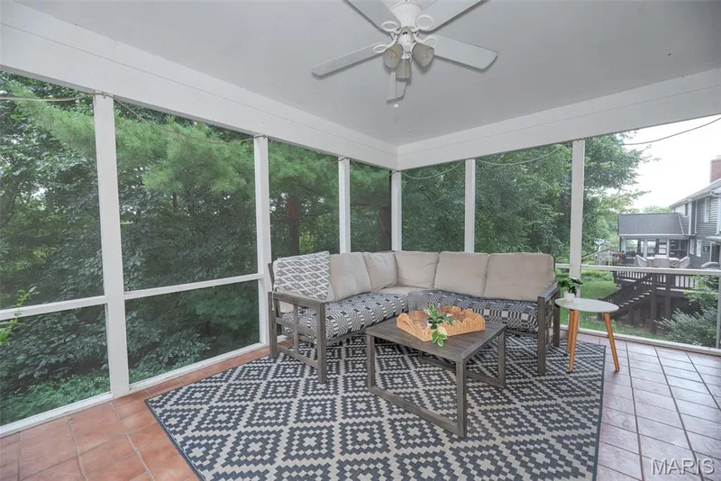 Screened porch featuring a ceiling fan, tiled flooring, and white painted structural elements — 1526 Candish Lane, Chesterfield, MO 63017