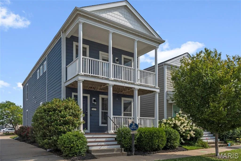 Two-story residence featuring a blue siding exterior, a double-tiered front porch with white columns and railings, and a prominent front gable — 3429 Sublette Street, St Charles, MO 63301