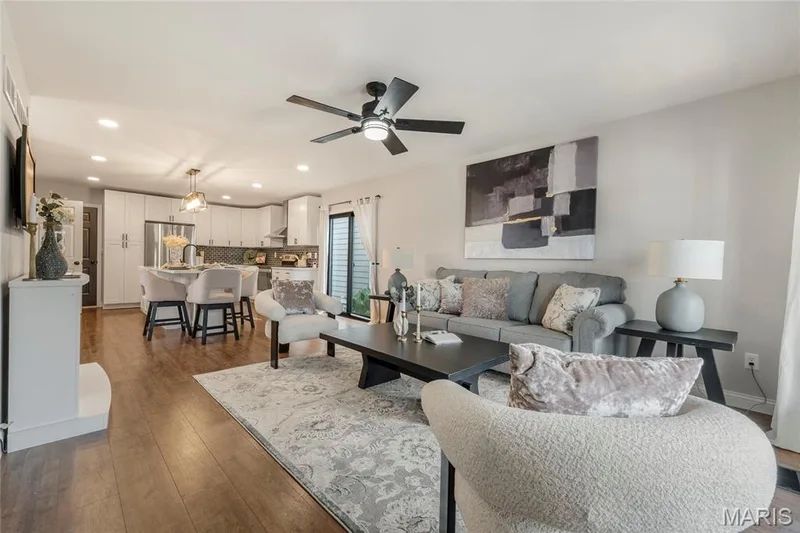 Open-concept living area featuring wood-finish flooring, a contemporary ceiling fan, recessed lighting, and a white fireplace mantel — 3429 Sublette Street, St Charles, MO 63301