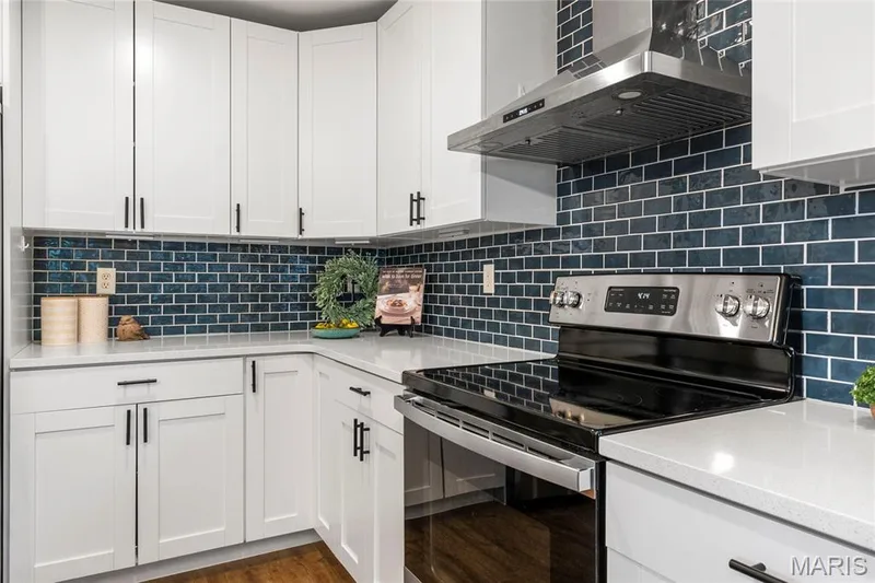 Modern kitchen featuring white shaker cabinetry with black hardware, a stainless steel range with a glass cooktop, and a matching stainless steel range hood — 3429 Sublette Street, St Charles, MO 63301