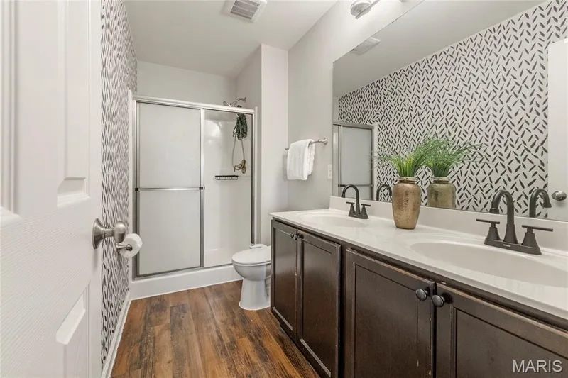 Bathroom featuring a double vanity with white countertops, dark wood-finish cabinetry, and matte black faucets — 3429 Sublette Street, St Charles, MO 63301