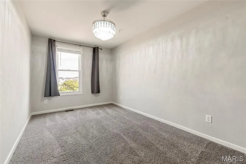 Carpeted room featuring a single window with a white frame and a crystal chandelier — 3429 Sublette Street, St Charles, MO 63301