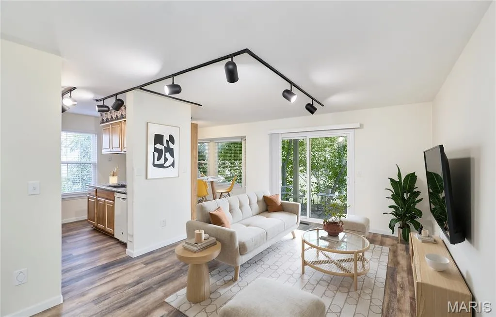 Open-concept living area with wood-finish flooring, track lighting, and a sliding glass door — 146 Old Buggy Court #A, St Charles, MO 63304