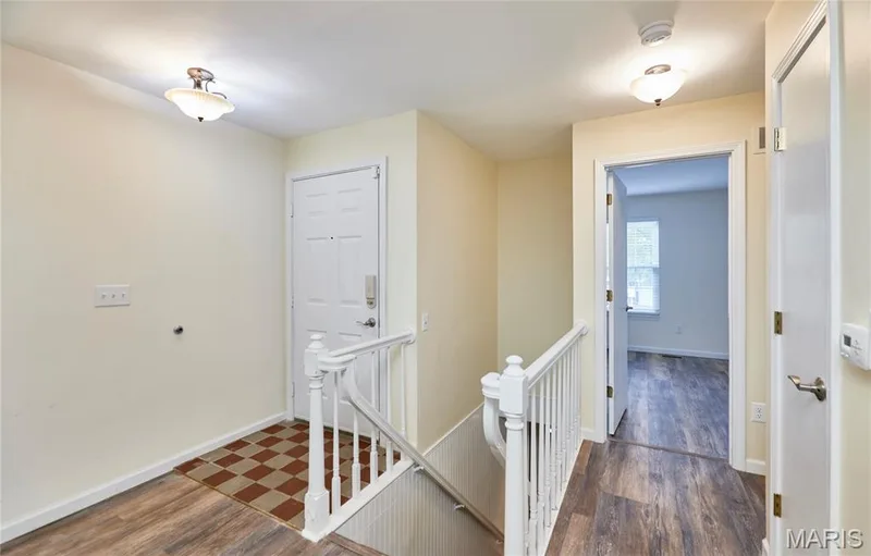 Entryway featuring wood-finish flooring, white paneled doors, and a staircase with a white railing — 146 Old Buggy Court #A, St Charles, MO 63304