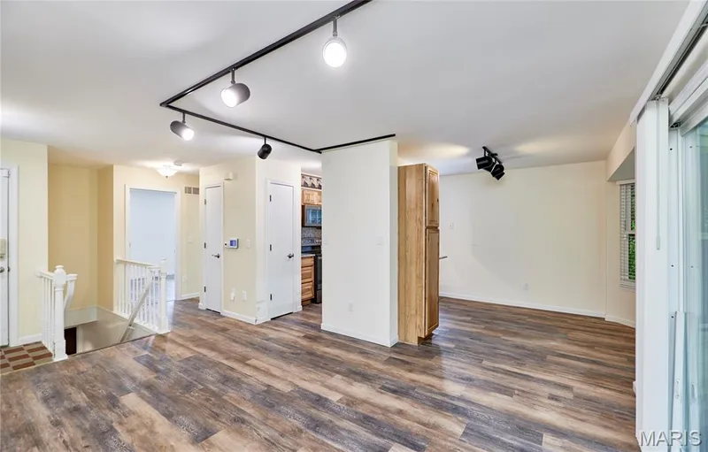 Wood-finish flooring throughout, track lighting, white railing, and sliding glass door — 146 Old Buggy Court #A, St Charles, MO 63304