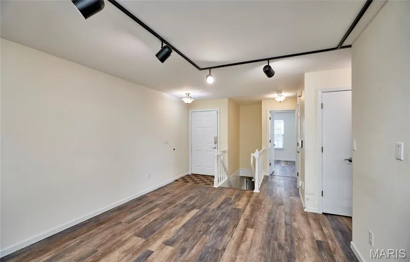 Wood-finish flooring, white walls, black track lighting, and a white front door with a checkered tile entry — 146 Old Buggy Court #A, St Charles, MO 63304