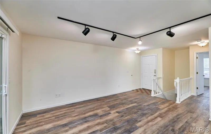 Wood-finish flooring, track lighting, white paneled door, sliding glass door, and white painted balustrade — 146 Old Buggy Court #A, St Charles, MO 63304