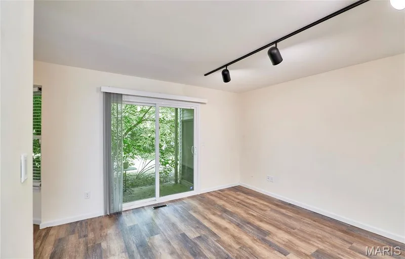 Wood-finish flooring with a neutral wall color, sliding glass door, and track lighting — 146 Old Buggy Court #A, St Charles, MO 63304