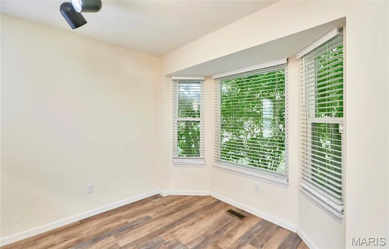 Bay windows with white blinds, wood-finish flooring, and a ceiling-mounted light fixture — 146 Old Buggy Court #A, St Charles, MO 63304