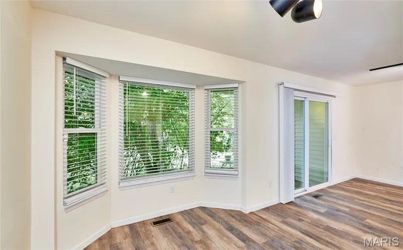 Bay window with white blinds, wood-finish flooring, and a sliding glass door — 146 Old Buggy Court #A, St Charles, MO 63304