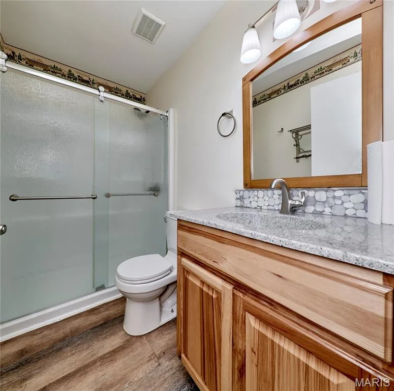 Wood-finish flooring with a vanity featuring a light-toned wood finish, a granite-finish countertop, and an undermount sink — 146 Old Buggy Court #A, St Charles, MO 63304