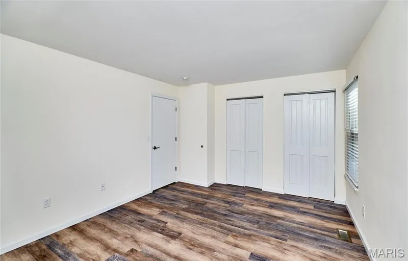 Wood-finish flooring, white walls, two bi-fold closet doors, and a single window with blinds — 146 Old Buggy Court #A, St Charles, MO 63304
