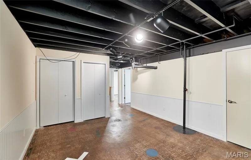 Exposed ceiling beams with track lighting, multiple bi-fold closet doors, painted concrete flooring, and wainscoting — 146 Old Buggy Court #A, St Charles, MO 63304