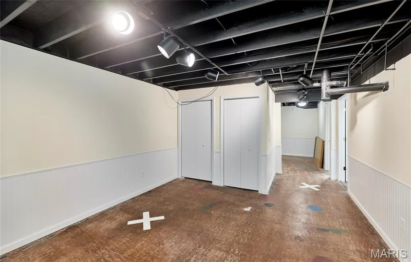 Track lighting illuminates the space, featuring a dark exposed ceiling and light wall color — 146 Old Buggy Court #A, St Charles, MO 63304