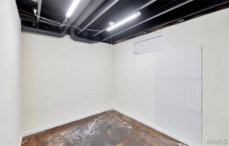 Painted exposed ceiling joists with utility pipes, fluorescent lighting, white painted walls, and a small window with blinds — 146 Old Buggy Court #A, St Charles, MO 63304