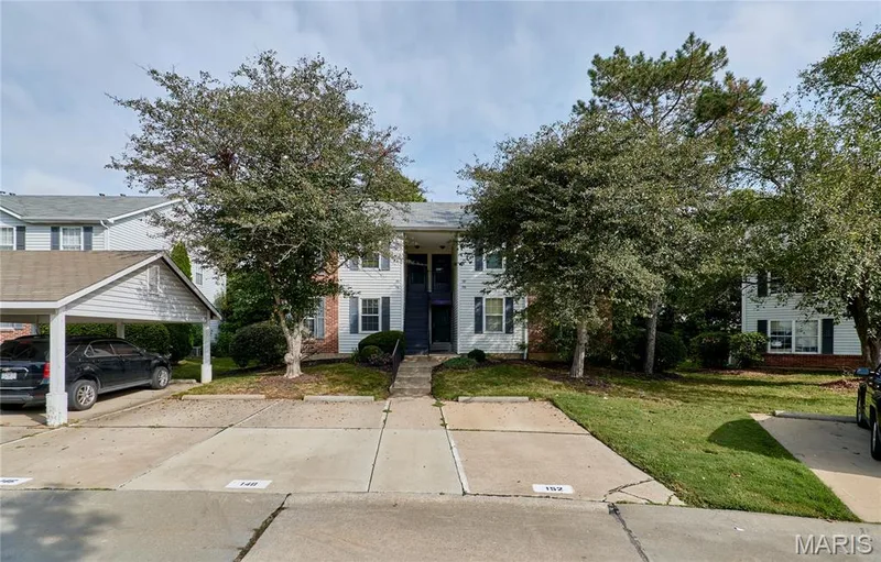 Two-story exterior with white siding, dark shutters, and a covered carport — 146 Old Buggy Court #A, St Charles, MO 63304