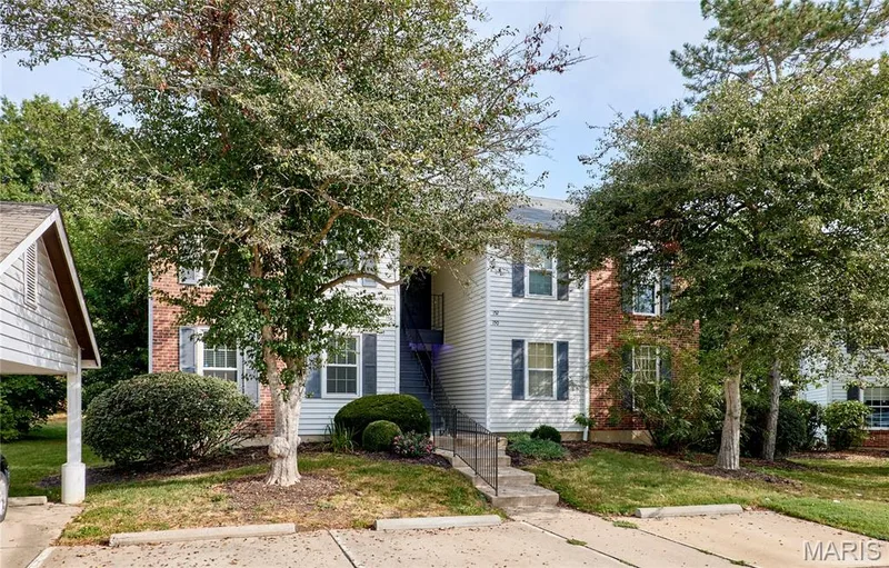 Brick and siding exterior with dark shutters, established trees, concrete steps, and a carport — 146 Old Buggy Court #A, St Charles, MO 63304