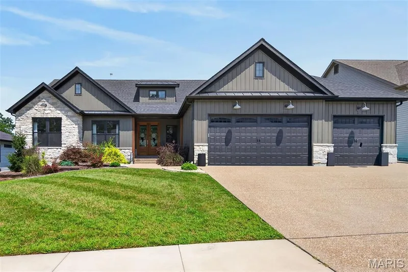 Impressive Front Elevation with Stone, Board and Batten Siding, Carriage Style Garage Doors, Landscaping and Lawn Irrigation — 517 Stonewolf Creek Drive, Wentzville, MO 63385