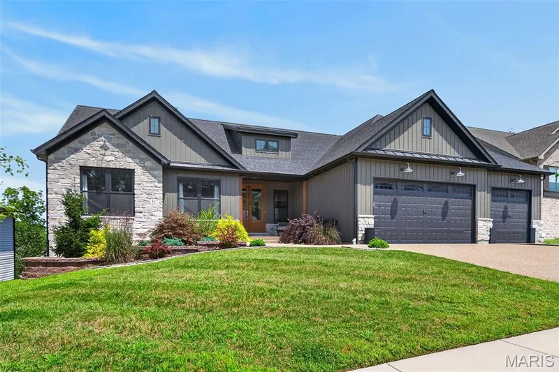 Dynamic Front Elevation with Stone, Board and Batten Siding, Carriage Style Garage Doors and Professional Landscaping — 517 Stonewolf Creek Drive, Wentzville, MO 63385