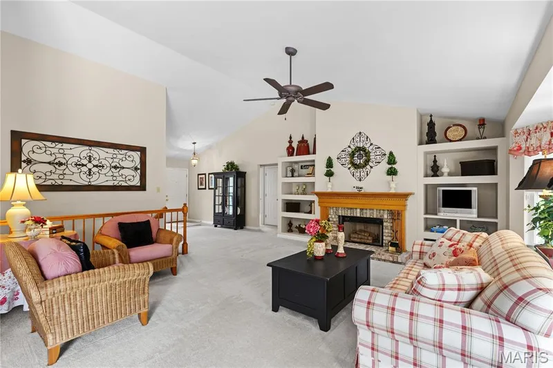 View of great room showing fireplace with built-in bookcases and open stairs to lower level — 8 Autumn Grove Court, O'Fallon, MO 63366