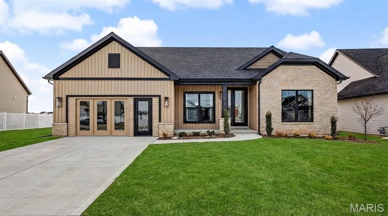 Modern ranch-style residence featuring a stone and board-and-batten facade, black-framed windows, a covered entry, and a concrete driveway — 312 Summer Glen Lane, St Charles, MO 63301