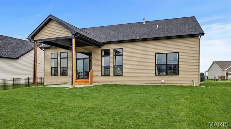 Exterior featuring beige horizontal siding, a dark shingle roof, and a covered patio with natural wood support beams — 312 Summer Glen Lane, St Charles, MO 63301