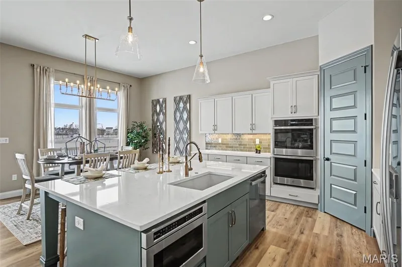 Contemporary kitchen featuring a large central island with a built-in microwave, light-toned countertops, and an undermount sink — 312 Summer Glen Lane, St Charles, MO 63301